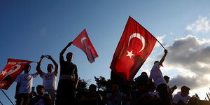 Menschen schwingen die türkische Fahne im Gegenlicht