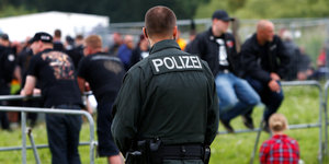 Ein Polizist am steht in der Nähe eines Festivalgeländes. Er dreht der Kamera den Rücken zu