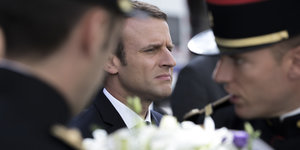 Emmanuel Macron im Hintergrund zwischen zwei Soldaten
