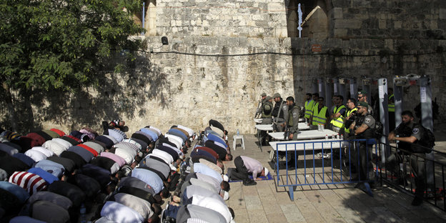 Muslime knien betend vor israelischen Polizisten