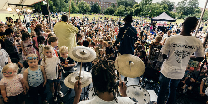 Kinder auf und vor einer Bühne, auf der eine Band spielt