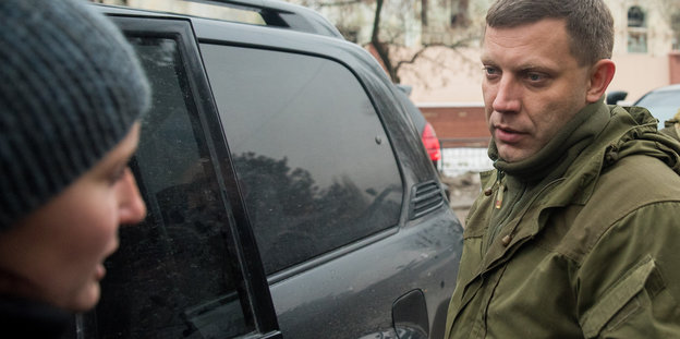 Alexander Sachartschenko steht neben einem Auto und spricht mit einem Menschen