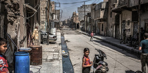 Kinder auf einer Straße, alle Gebäude sind zerstört