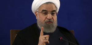 Mann mit Turban, Brille und erhobenem Zeigefinger - es ist der iranische Präsident Hassan Ruhani