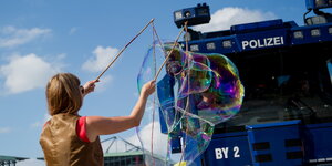 eine Frau steht vor einem Wasserwerfer und macht riesige Seifenblasen