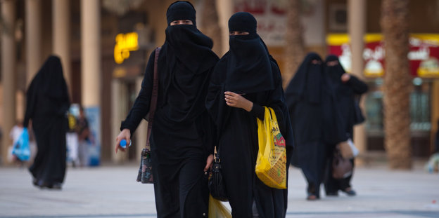 Frauen beim Shopping, die einen schwarzen Ganzkörperschleier tragen