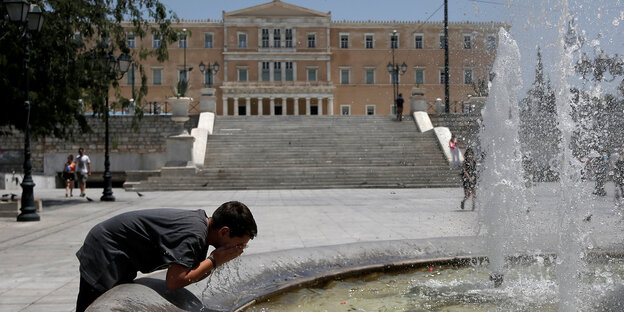 Ein Mann erfrischt sich an einem Brunnen in Athen