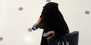 Eine verschleierte Frau läuft mit Einkaufstasche