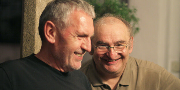 Zwei Männer stehen nebeneinander und lachen Zwei Männer stehen nebeneinander und lachen