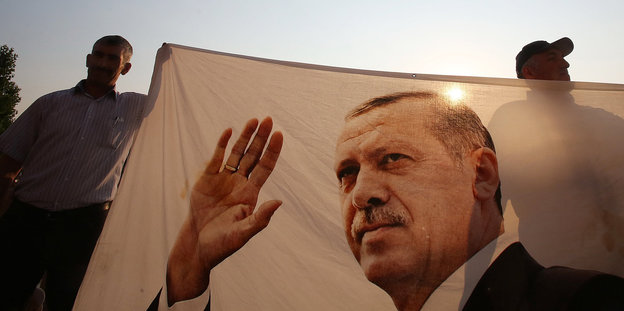 Zwei Männer halten ein Tuch mit dem Foto des türkischen Präsidenten Recep Tayyip Erdogan