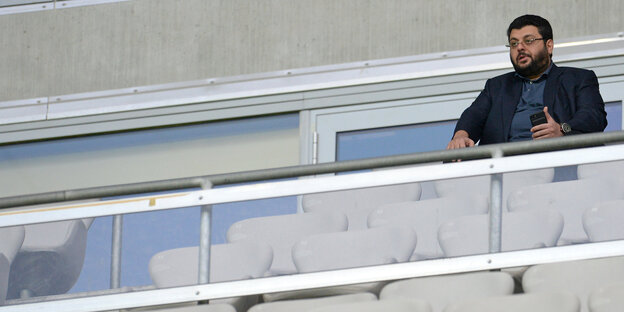 Ein Mann steht auf einem Balkon mit gläserner Brüstung