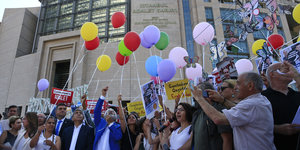 mehrere Personen mit Protestschildern und Luftballons