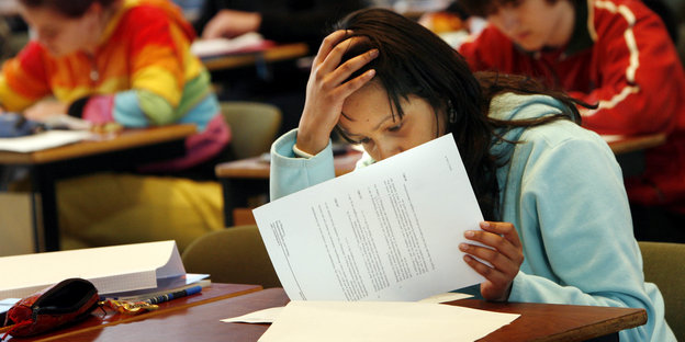 Eine Schülerin hält sich eine Hand an die Stirn und sieht eine Prüfung durch