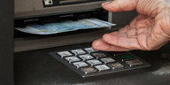 Eine Hand nimmt einen Zwanzig-Euro-Schein aus einem Bankautomaten