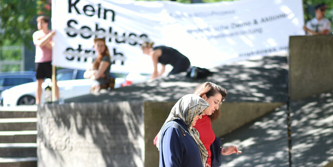 Kein Schlussstrich steht auf einem weißen Transparent, davor stehen Frauen und Männer