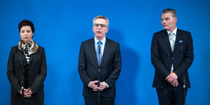 Drei Menschen stehen vor einer blauen Wand