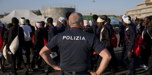 Ein italienischer Polizist beobachtet Flüchtlinge aus Afrika in einem Hafen
