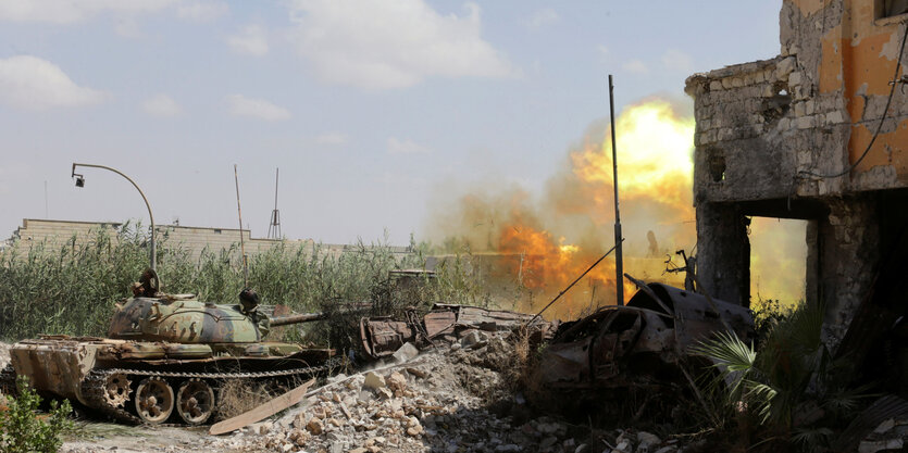 Ein Panzer vor einer Explosion und einem kaputten Gebäude