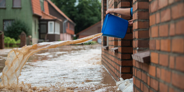 Eimer Wasser wird aus einem Fenster gekippt Eimer Wasser wird aus einem Fenster gekippt