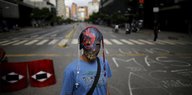 Ein maskierter Mann mit Rosenkränzen steht auf einer leeren Straße