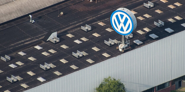 Ein Industriegebäude mit einem großen VW-Logo auf dem Dach aus der Vogelperspektive