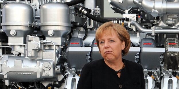 Angela Merkel steht vor einem großen Dieselmotor