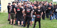 Kräftig gebaute Männer in schwarz-weiß-roten Band-T-Shirts stehen auf einer Wiese