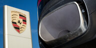 Der Auspuff eines Porsche Cayenne neben dem Logo von Porsche