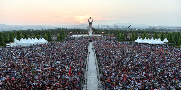 Eine Menschenmenge steht vor einem Präsidentenpalast vor einer untergehenden Sonne
