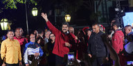 Präsident Maduro steht im roten Pulli vor einer Gruppe Menschen und winkt