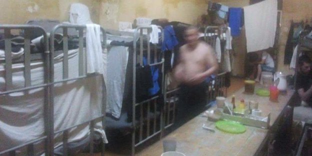 Ein nicht zu erkennender Mann durchschreitet einen Schlafsaal in der Arbeitskolonie LIU-19 im russischen Mordwinien.