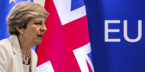 Die Premierministerin vor einer Union-Jack-Fahne und dem EU-Schriftzug