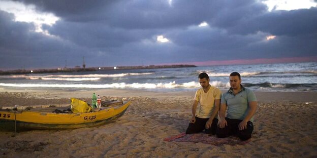 Zwei Männer beten am Strand