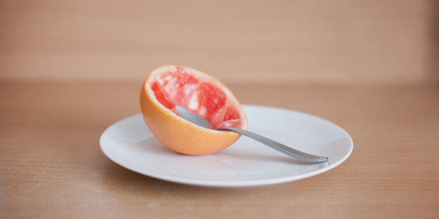 Eine ausgelöffelte Grapefruithälfte liegt auf einem Teller