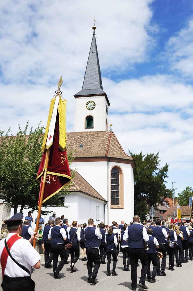 Eine Blaskapelle zieht an einer Kirche vorbei