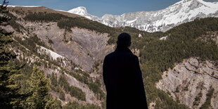 Die Silhouette eines Mannes ist vor einer Gebirgslandschaft zu erkennen