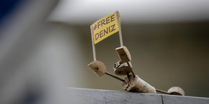 Eine Figur aus Korken hält ein Schild, auf dem „Free Deniz“ steht