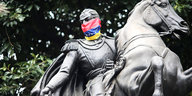 Ein Reiterstandbild. Dem Reiter wurde eine venezolanische Flagge um die untere Gesichtspartie gebunden.