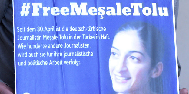 Eine Person hält ein Plakat auf dem das Bild von Mesale Tolu zu sehen ist. Daneben steht #Free Mesale Tolu