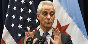 Chicagos Bürgermeister steht vor einer US- und einer Stadtflagge und hebt ablehnend beide Hände