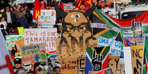Viele bunte Plakate und Banner ragen bei einer Demonstration gegen Jacob Zuma aus einer Menschenmenge