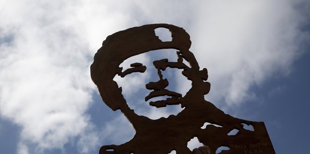 Ein Scherenschnitt von Hugo Chávez vor blauem Himmel mit Wolken