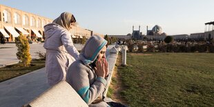 Auf dem Königsplatz in Isfahan sitzen zwei Frauen im Abendlicht.