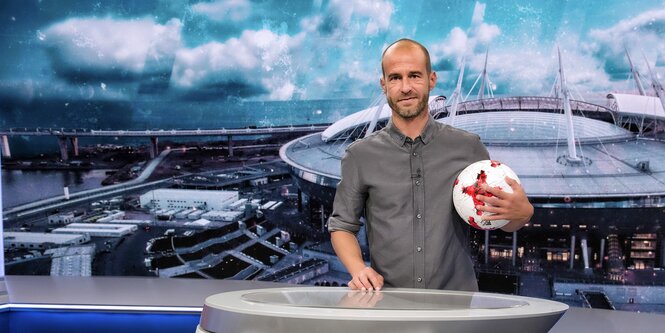 Mehmet Scholl steht mit einem Ball unter dem Arm im ARD-Studio