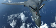 Ein Militärflugzeug in der Luft, im Hintergrund ein paar Wolken