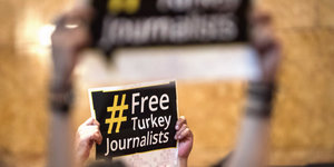 Hände halten ein Schild mit der Aufschrift "Free Turkey Journalists"