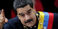 Ein Mann mit einer Schärpe in den Nationalfarben Venezuelas und erhobenem rechten Zeigefinger