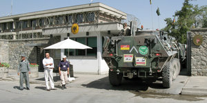 Ein gepanzertes Fahrzeug fährt auf das Gelände der deutschen Botschaft in Kabul, Afghanistan. Einige Menschen stehen vor dem Gelände