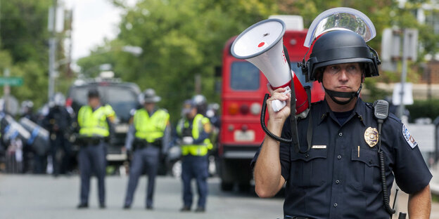 Ein Polizist hält ein Megafon