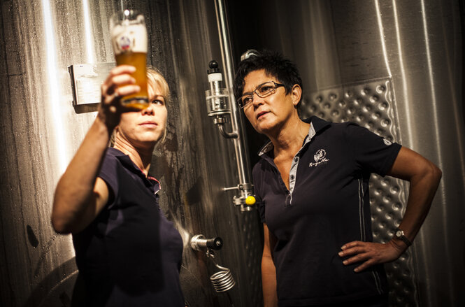 Zwei Frauen schauen ein Glas Bier an.